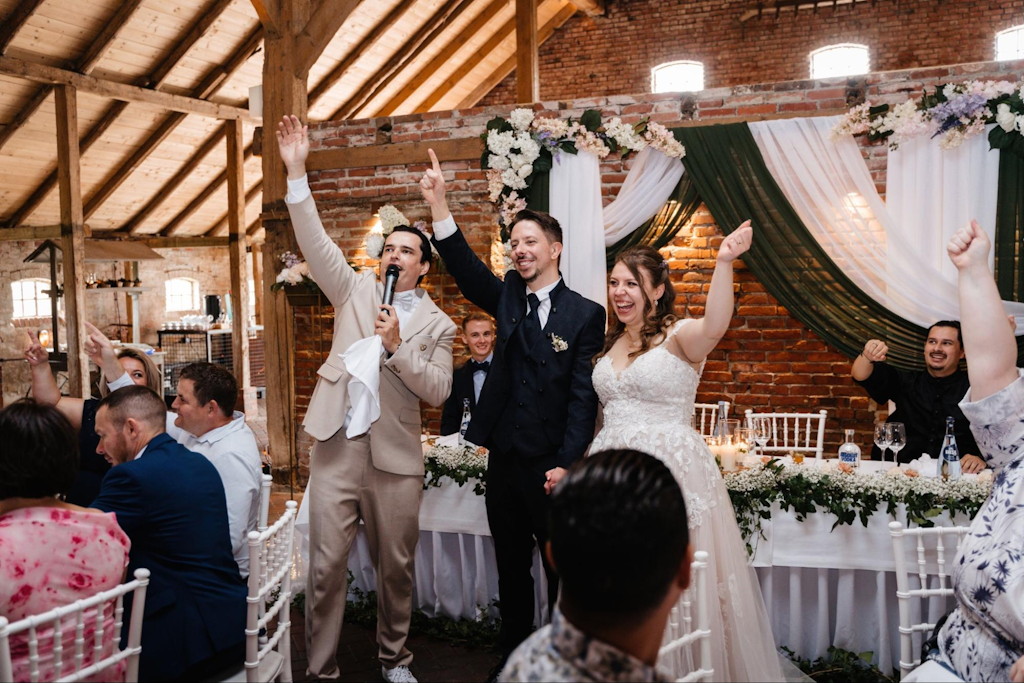 Russische Tamada aus M&uuml;nchen moderiert einen Toast mit dem jubelnden Brautpaar bei einer deutsch-russischen Hochzeit