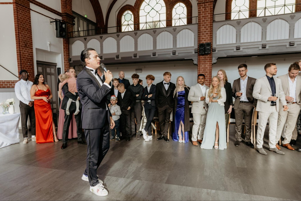 Russischer Tamada aus M&uuml;nchen moderiert vor versammelten G&auml;sten unterschiedlichen Alters bei einer deutsch-russischen Hochzeit